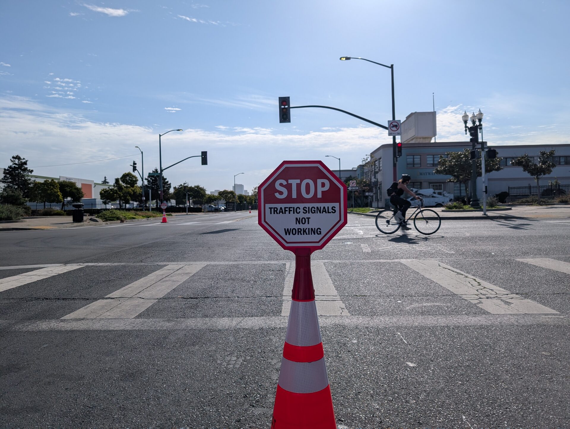 A sign reading Stop, Traffic Signals Not Working, mounted on a traffic cone at an intersection